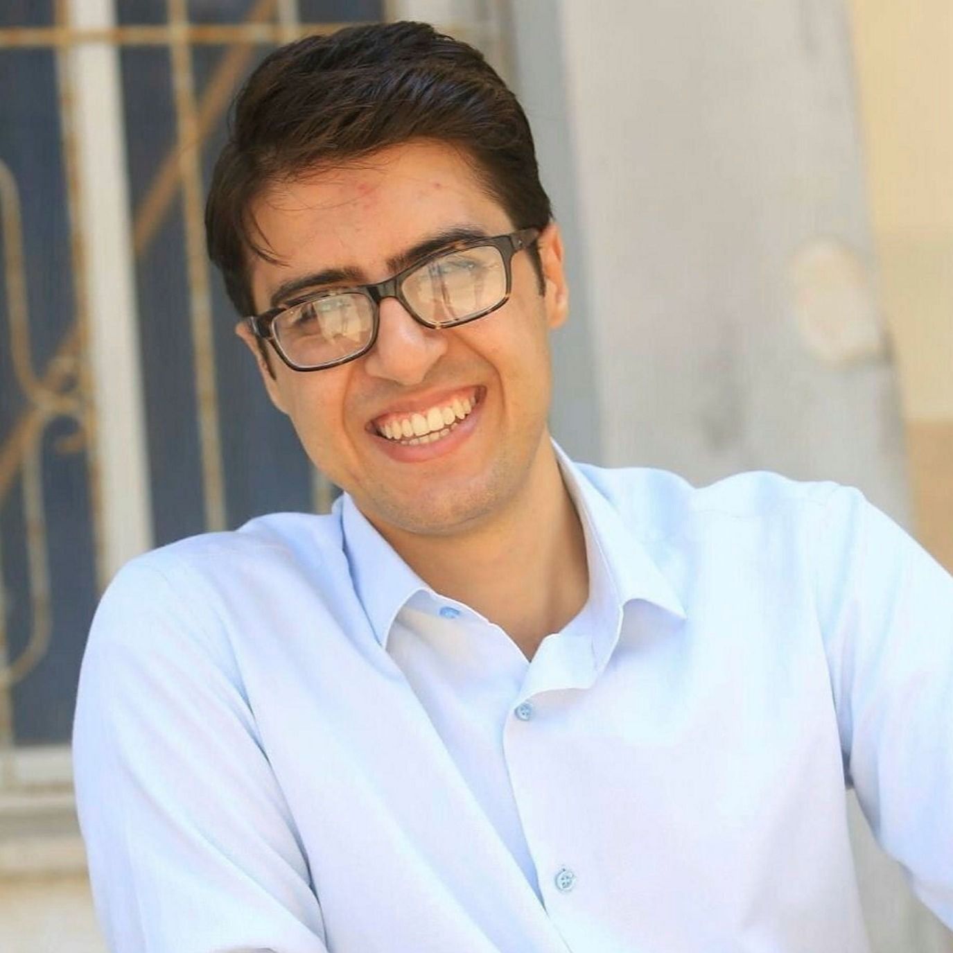 A young man in a blue shirt smiles for the camera