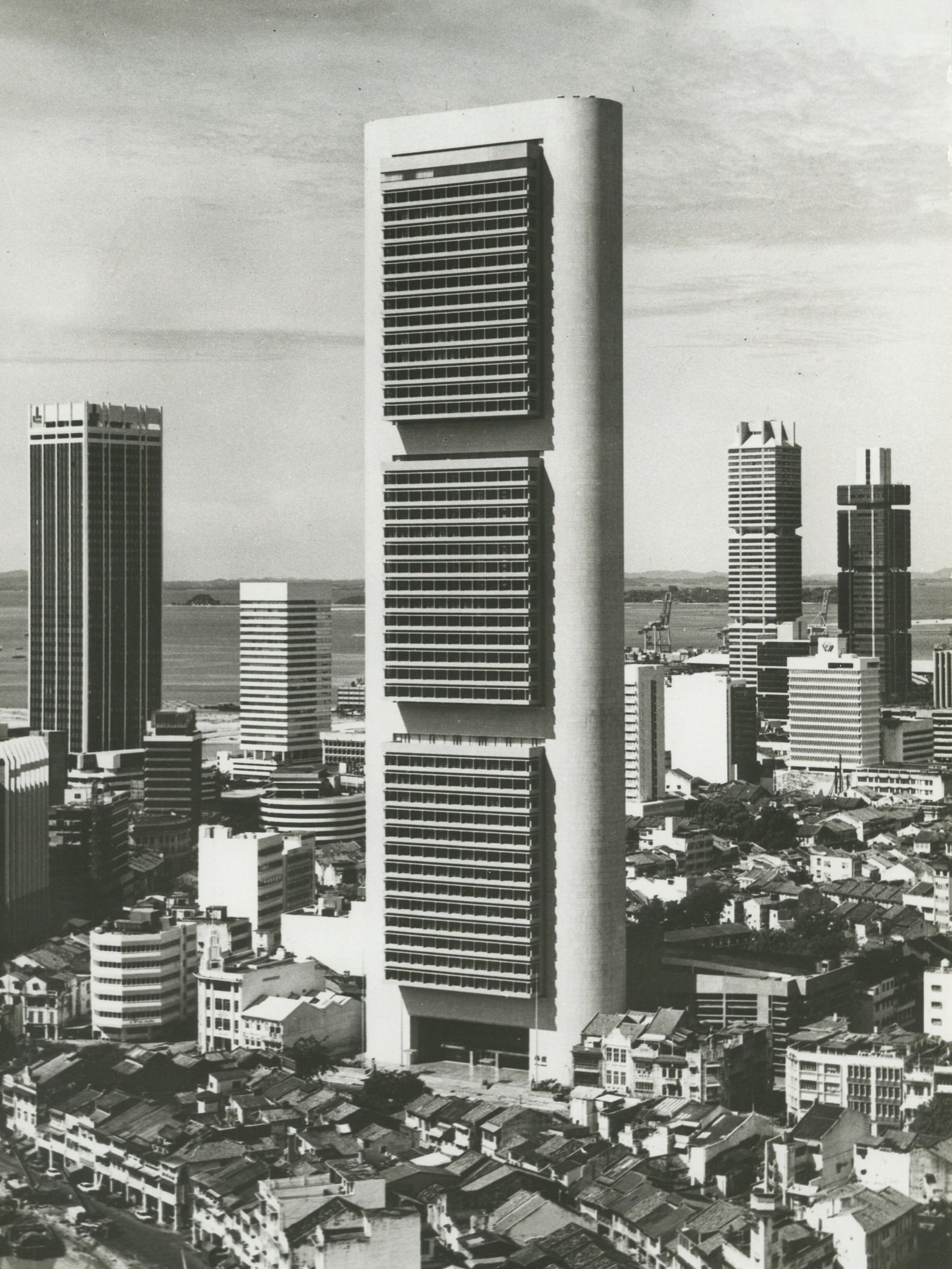 Black and white photo of a skyscraper which looks like a tall but thin white slab with three separate black fields of windows